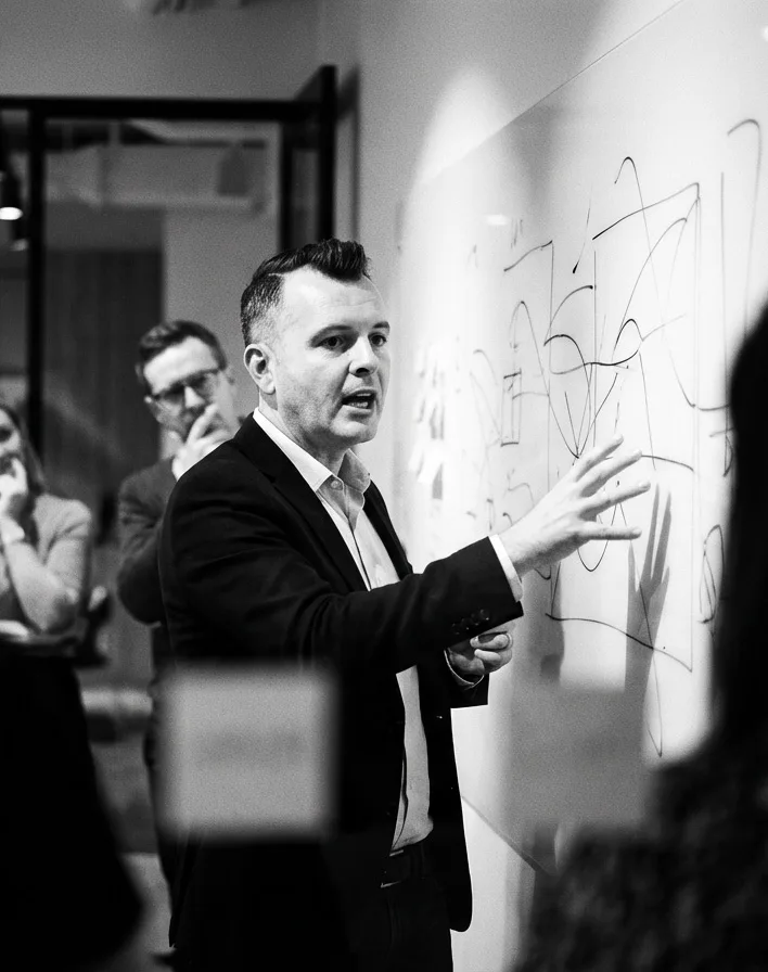 Abstract Creative principal mapping a brand strategy on a whiteboard during a client workshop